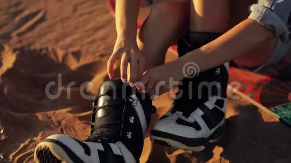 女孩把鞋子系在木板上把设备系好站起来拿起木板离开把脚靴合上视频的预览图