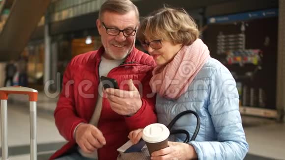 成熟的灰胡子男人给妻子看了一张智能手机上的照片两个人都开心地笑着讨论它快乐视频的预览图