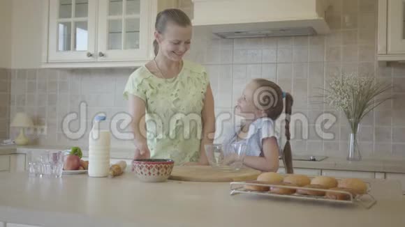 美丽的年轻妈妈和小可爱的女儿一起在厨房做饭家庭幸福关系妈妈和视频的预览图