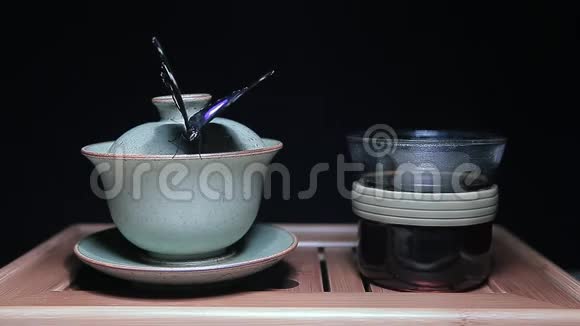茶杯蝴蝶竹桌深色背景高清镜头视频的预览图