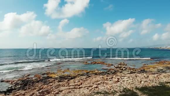 海浪撞击岩石海滩的空中拍摄蓝天天边白云塞浦路斯帕福斯风日晴朗视频的预览图