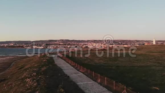 空中无人驾驶飞机在塞浦路斯帕福斯沿着地中海和灯塔拍摄的行人小径视频的预览图