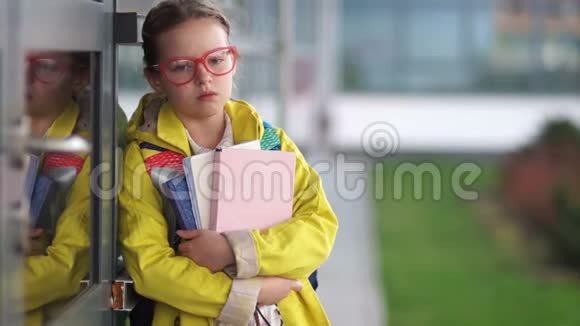 一个疲惫的女学生手里拿着书的肖像一个穿着黄色夹克的女孩戴着红色边框的眼镜和一个视频的预览图