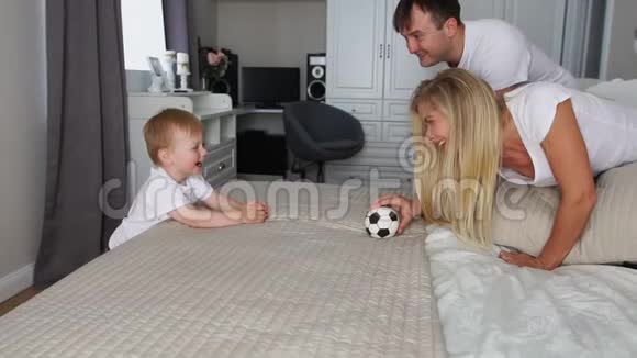 爸爸和妈妈在床上和男孩一起玩球视频的预览图
