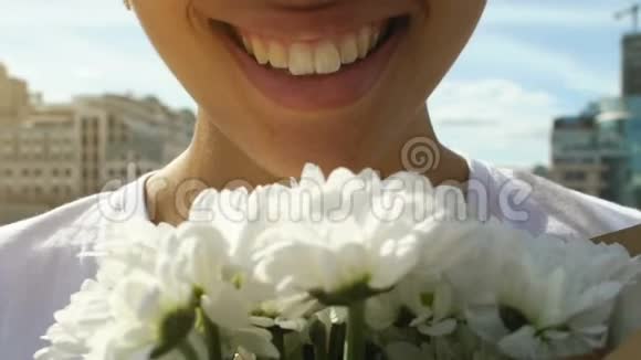 漂亮的美国黑人女人嗅着白花的香气微笑着靠近视频的预览图