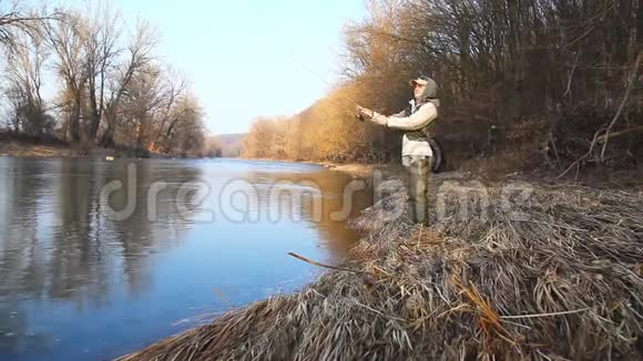 一个女人站在河堤上钓着一条旋转的鱼视频的预览图