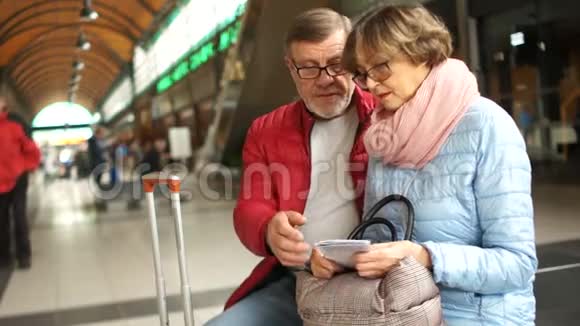 旅行者夫妻在火车站的大楼里坐在长凳上用一张时间表检查车票视频的预览图