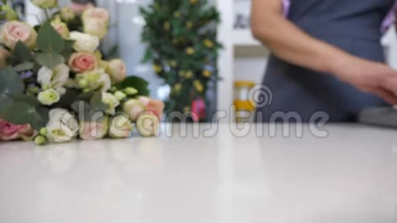 花商在桌子上卷一张纸包裹着一束玫瑰特写视频的预览图