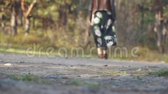 穿着长裙子带着鲜花的女孩走在地上的路上在户外散步的女人视频的预览图