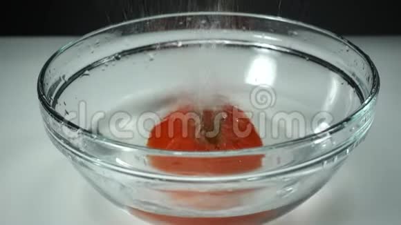 成熟多汁的番茄在白色背景下落入清澈的碗中缓慢运动视频的预览图