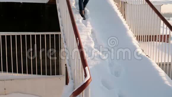 穿着带毛衣罩的蓝色夹克衫的女人从雪梯上下来前景视频的预览图