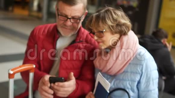 亲密肖像成熟男女浏览照片在手机养老金领取者穿着春季夹克和视频的预览图