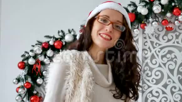 美丽的年轻女子戴着圣诞老人的帽子和眼镜参加圣诞节庆祝活动有魅力的女人傻视频的预览图