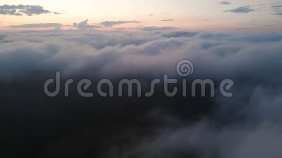 日落后在蓝色的小时低键鸟瞰傍晚飞越云层和山上的概念视频的预览图