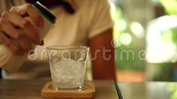 女人用手把软饮料倒在一杯冰里视频的预览图