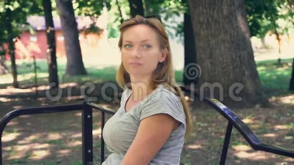 一个年轻的蓝眼睛女人坐在公园的长凳上的肖像4慢镜头视频的预览图