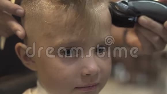 在理发店里用电动剃须刀剪画像小男孩幼儿剪发观念儿童视频的预览图