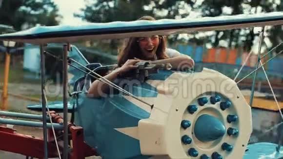 美丽微笑的年轻女孩戴着太阳镜骑着儿童旋转木马近景慢动作漂亮的女孩视频的预览图