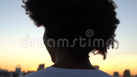在城市欣赏日落的美丽女人的后景站在屋顶上休息视频的预览图