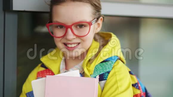 特写一位戴眼镜的漂亮女学生的肖像手里拿着书回到学校视频的预览图