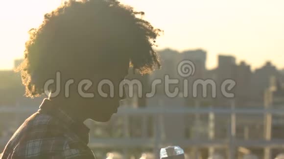 年轻的卷发美国黑人妇女在城市街道上喝水医疗保健视频的预览图