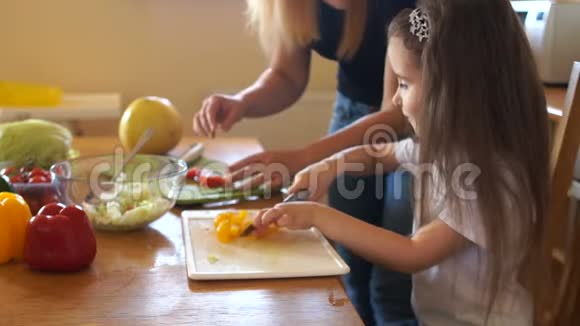 孩子们厨房里很有创造力妈妈和女儿在切沙拉的时候把一张滑稽的脸放在厨房里女孩是视频的预览图