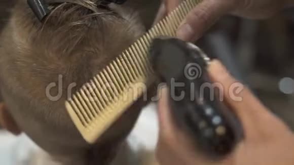 理发店用电动剃须刀和梳子剪孩子的头发在儿童沙龙里剪男孩发型男孩理发视频的预览图