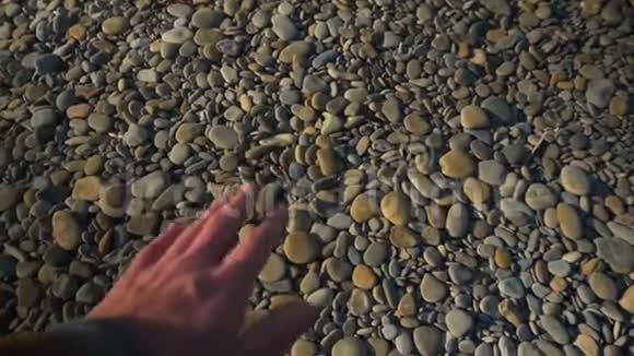 POV第一个人的视频一个人手拿着一块光滑的海石扔进海里视频的预览图