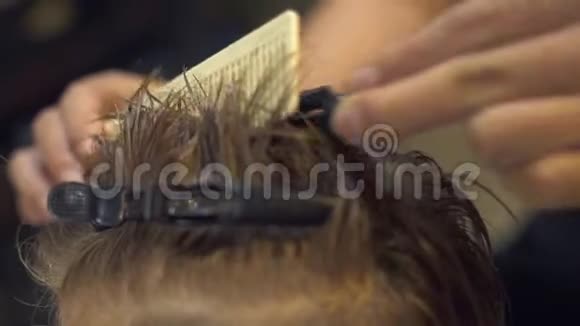 儿童理发师在理发店理发前对小男孩的头发进行梳理和固定儿童理发视频的预览图