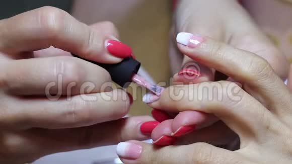 修指甲后涂粉白色指甲油特写观女钉画过程视频的预览图