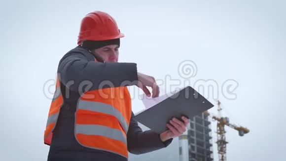 年轻英俊的工程师建筑师建筑工人商人戴着头盔穿着建筑背心用电话视频的预览图