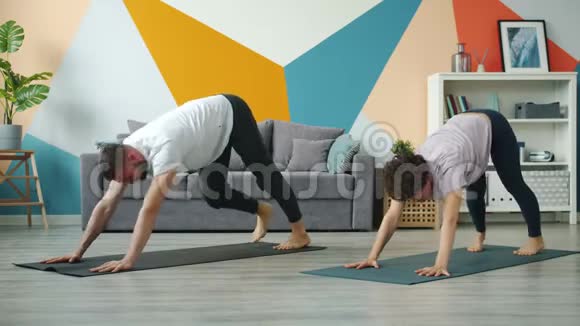 年轻夫妇在家做瑜伽一起在垫子上锻炼视频的预览图
