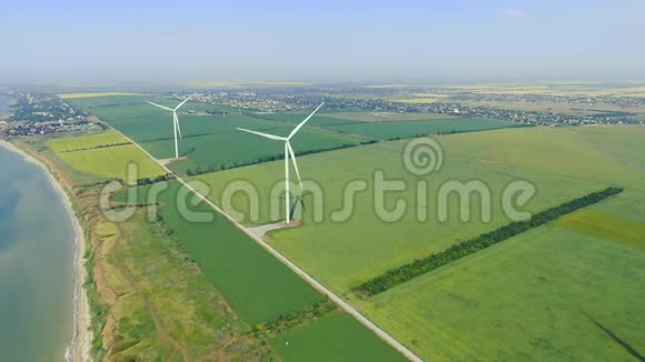 以城市为背景的绿色田野上的大型风力涡轮机视频的预览图