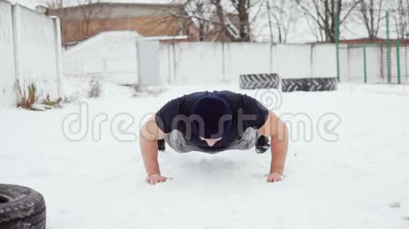 强壮的男人在雪地上做俯卧撑交叉锻炼视频的预览图