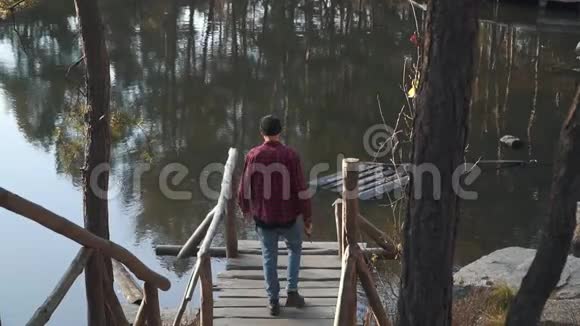 一个长着胡须的人手里拿着一把斧子走在桥边的湖边一个留胡子的家伙在户外拿着斧头视频的预览图