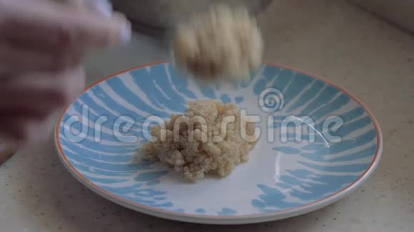 女人的手把藜麦粥放在盘子里特写镜头视频的预览图