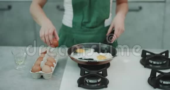 厨师穿着绿色围裙在平底锅里煮四个鸡蛋背景看起来很美观视频的预览图