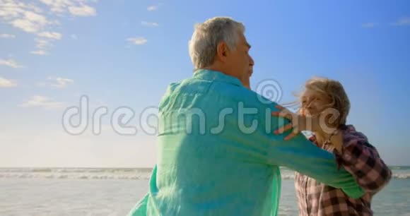 活跃的高加索夫妇在海滩上跳舞的侧面景色视频的预览图