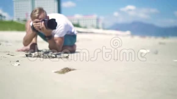 男摄影师拍摄年轻女子在沙滩上摆姿势的照片年轻的摄影师视频的预览图