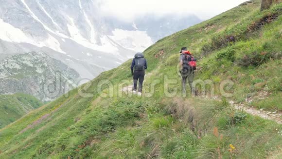 父子俩沿着山路走他们在高加索山脉旅行背着背包视频的预览图