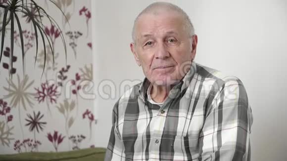一幅很老的人像在家看着4k相机视频的预览图