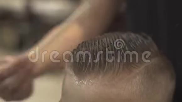 理发师在理发店里梳湿头发的小男孩用电动剃须刀剪头发儿童发型师视频的预览图