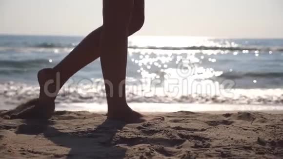 在阳光明媚的日子里雌性的脚在海边散步背景是波浪年轻女子踩在沙滩上的腿视频的预览图