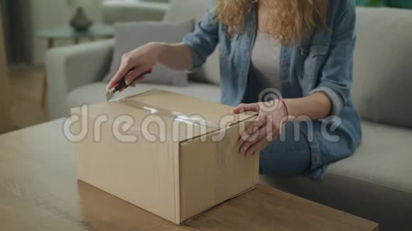 一个年轻女孩在客厅的沙发上打开一个纸板包裹视频的预览图