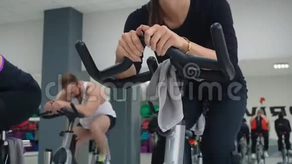 健身妇女在健身俱乐部自行车课上训练自行车机静态单车运动团体训练演习视频的预览图