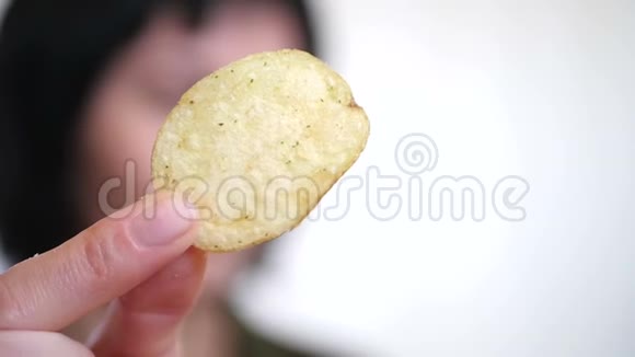 黑发女孩在白色背景下吃薯片特写女人手里拿着薯片特写然后放进去视频的预览图