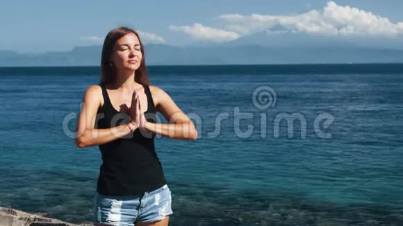 年轻美女做瑜伽运动的肖像背景海洋视频的预览图