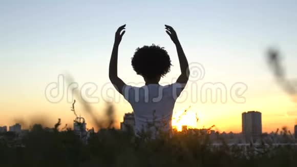 非裔美国女士练习瑜伽坐在莲花的位置日落在城市视频的预览图