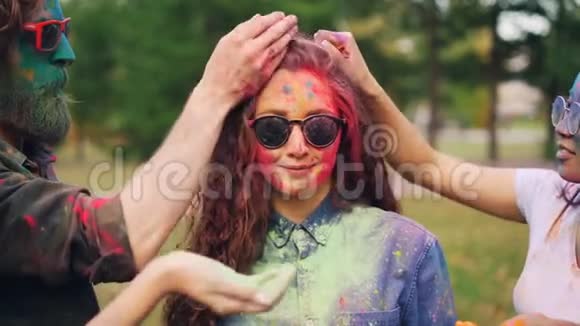 快乐的朋友在霍利节上用粉粉画漂亮女孩脸和头发女人在微笑视频的预览图