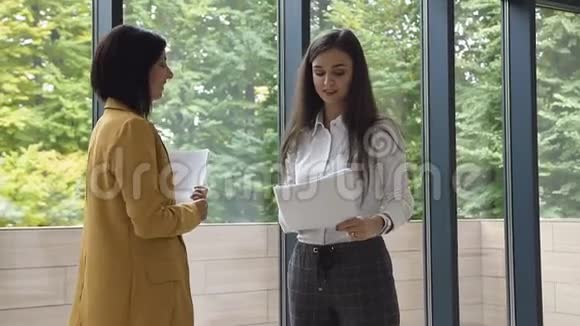 两位年轻成功的商务女性穿着严格的服装进行交易握手致意视频的预览图